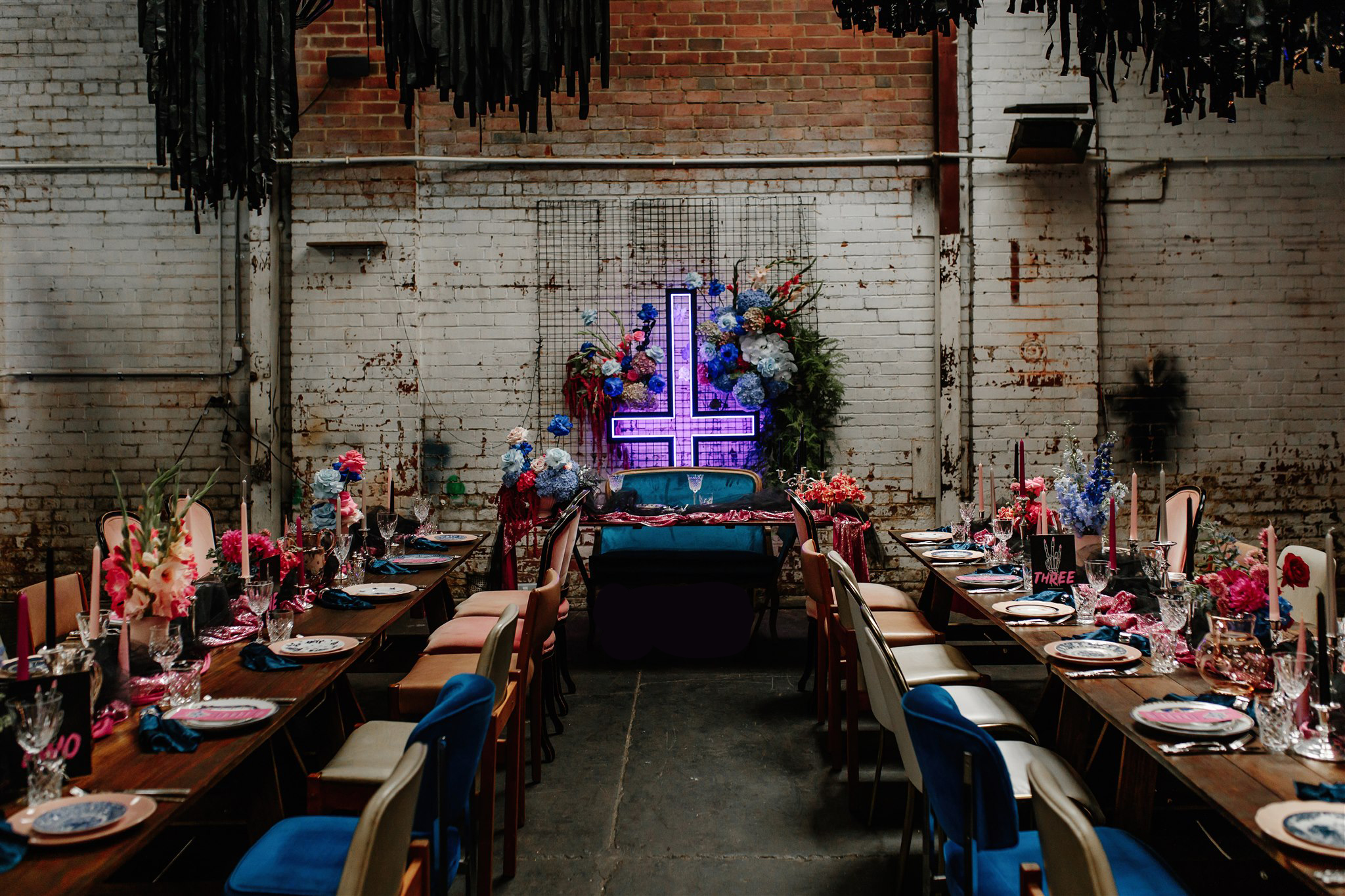 wooden backdrop with til death neon sign and greenery hanging over head for ceremony